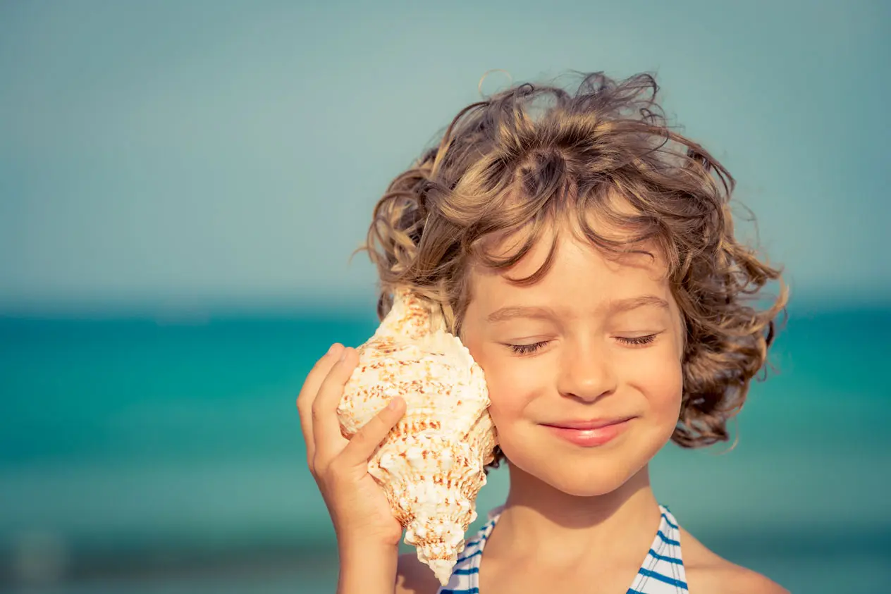 enfant qui écoute la mer dans un coquillage