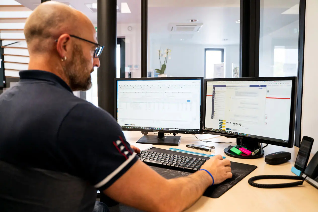 homme du service client derrière deux écrans d'ordinateur